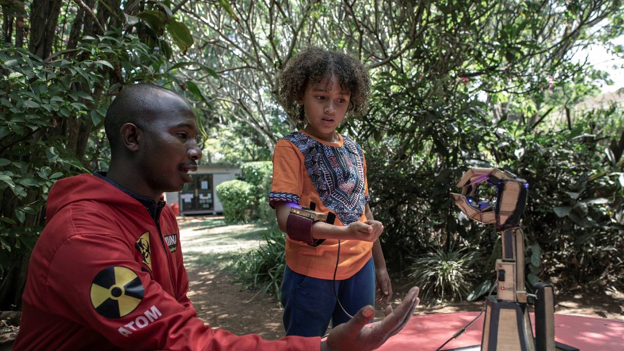 Moses Kiuna (gauche), 29 ans, montre un bras robotique à un enfant le 31 janvier 2023 à Nairobi, au Kenya